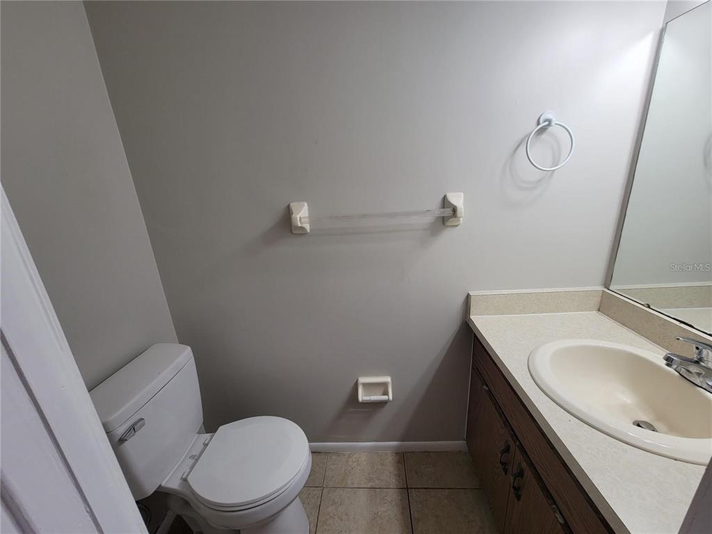 A bathroom features a toilet, a vanity with a sink, and a wall-mounted towel bar — 3625 NE 20TH PLACE, OCALA, FL