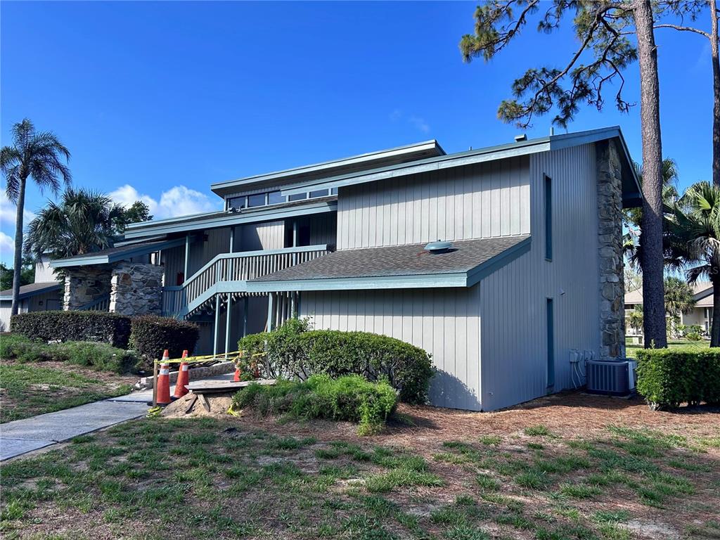 A two-story building with light gray vertical siding, stone accents, and an exterior wooden staircase — 2068 CORNER LAKE DRIVE, HAINES CITY, FL