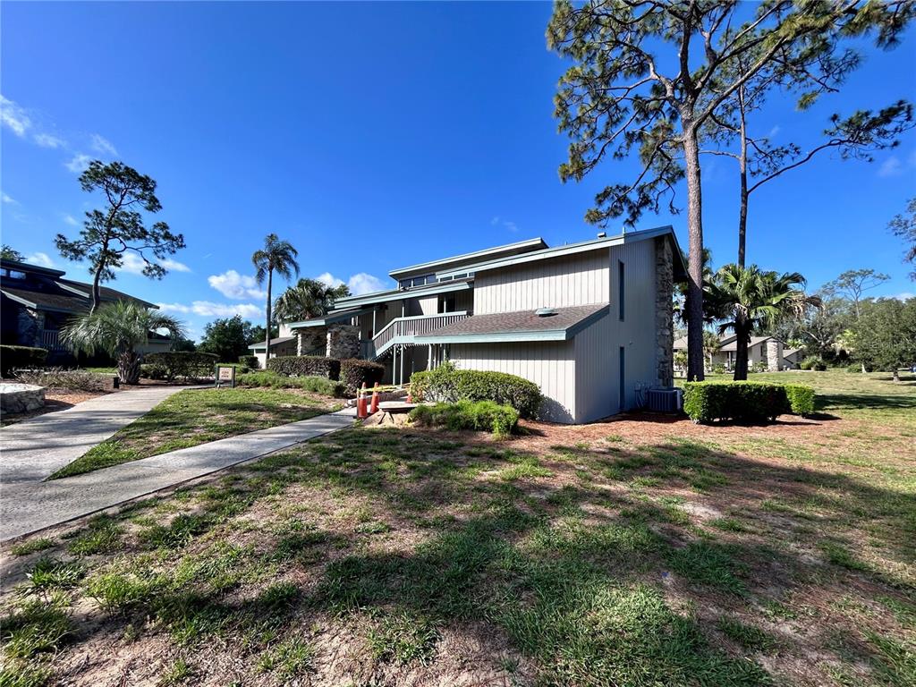 A two-story building with light-colored siding and a stone accent wall stands on a lawn — 2068 CORNER LAKE DRIVE, HAINES CITY, FL