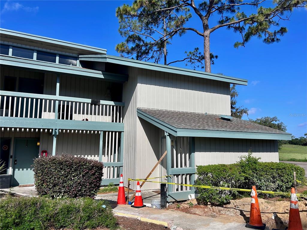 A two-story building exterior features light-colored vertical siding, a balcony, and yellow caution tape — 2068 CORNER LAKE DRIVE, HAINES CITY, FL