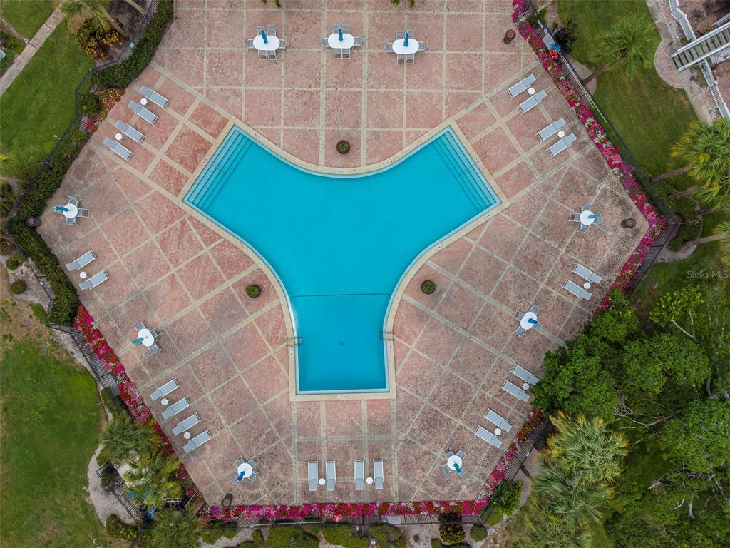 An aerial view shows a tri-lobed swimming pool surrounded by a paved deck and lounge chairs — 222 POMPANO DRIVE SE UNIT H, ST PETERSBURG, FL