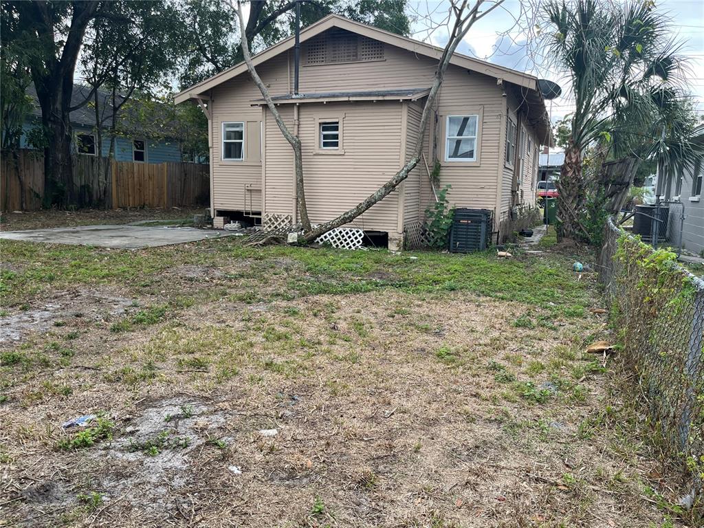 The exterior of a tan, single-story house with a yard and a chain-link fence — 201 W IDA STREET, TAMPA, FL