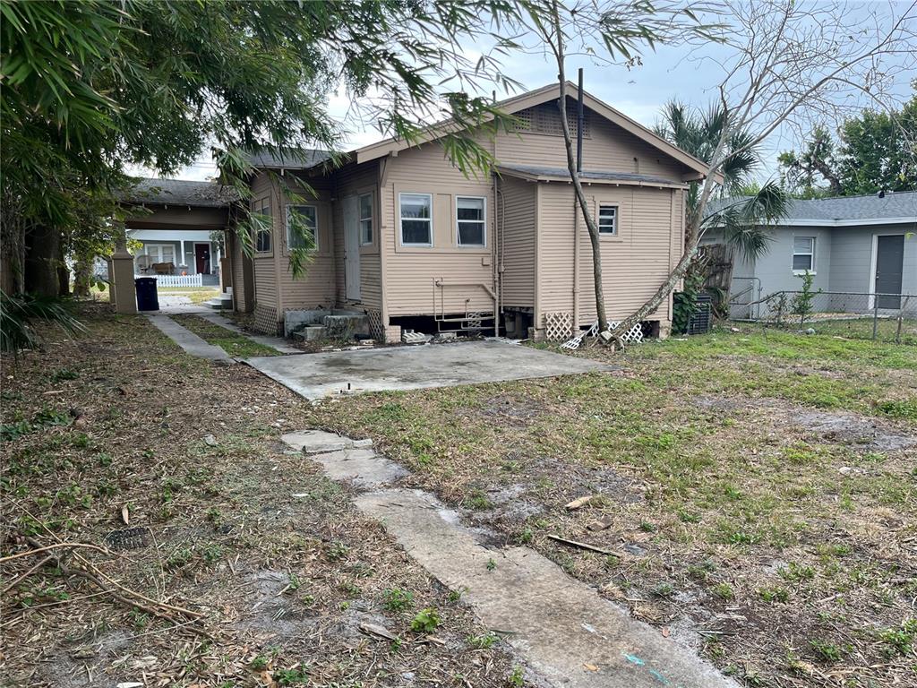 The exterior of a tan, single-story house with a concrete patio and a detached carport — 201 W IDA STREET, TAMPA, FL