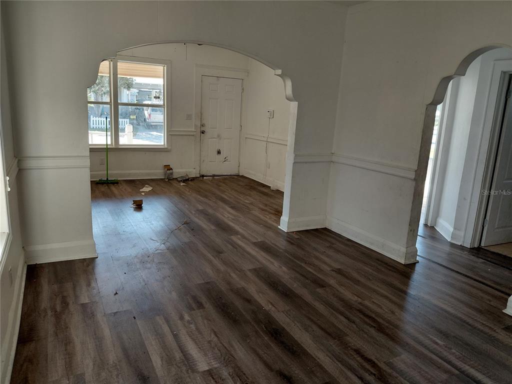 An interior view shows a room with wood-look flooring, white walls, and arched doorways — 201 W IDA STREET, TAMPA, FL