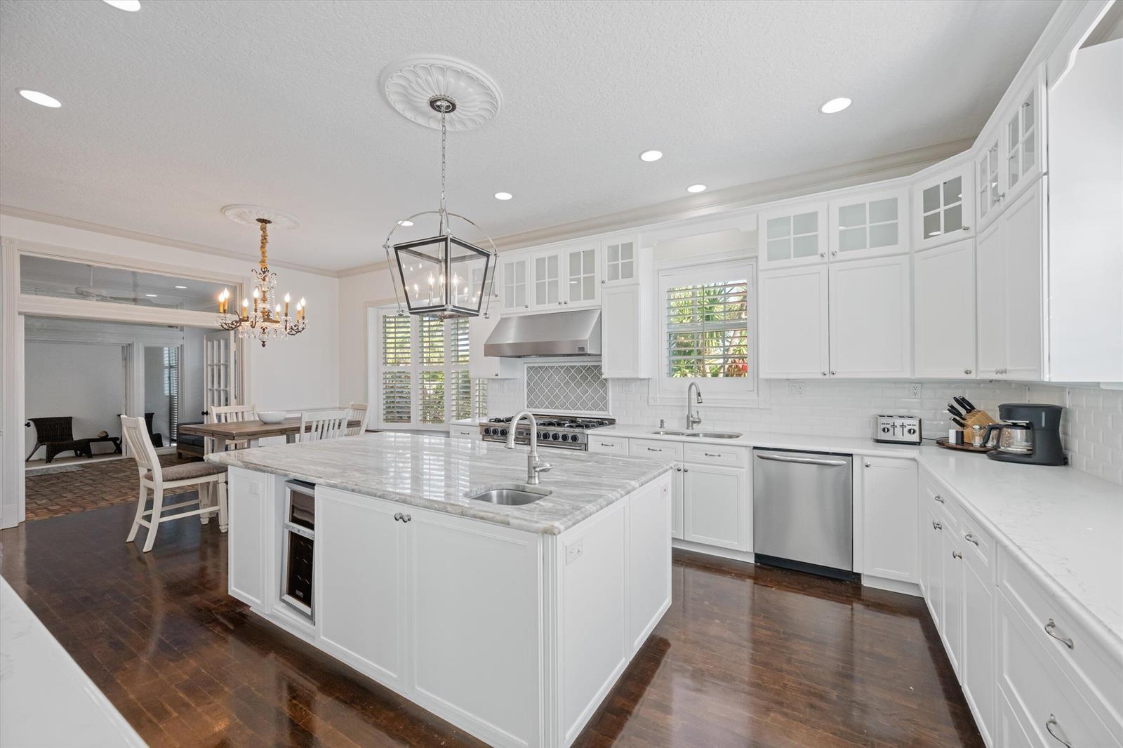A white kitchen features a large marble-topped island, stainless steel appliances, and dark hardwood floors — 401 Center Street, Jupiter FL 33458, JUPITER, FL