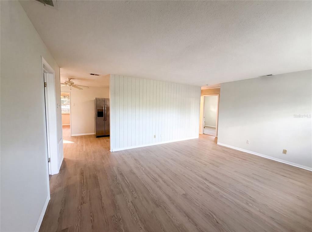 A living room with light wood-look flooring and a white vertical-paneled accent wall — 1436 ALABAMA AVENUE, HOLLY HILL, FL