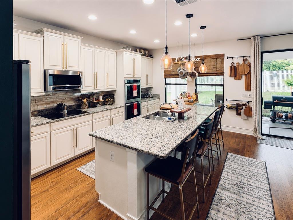 A kitchen with white cabinets, granite countertops, a large island, and stainless steel appliances — 726 WOODS LANDING DRIVE, MINNEOLA, FL