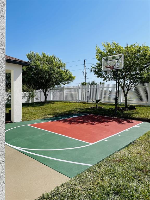 A backyard features a painted basketball court next to a white fence and trees — 726 WOODS LANDING DRIVE, MINNEOLA, FL