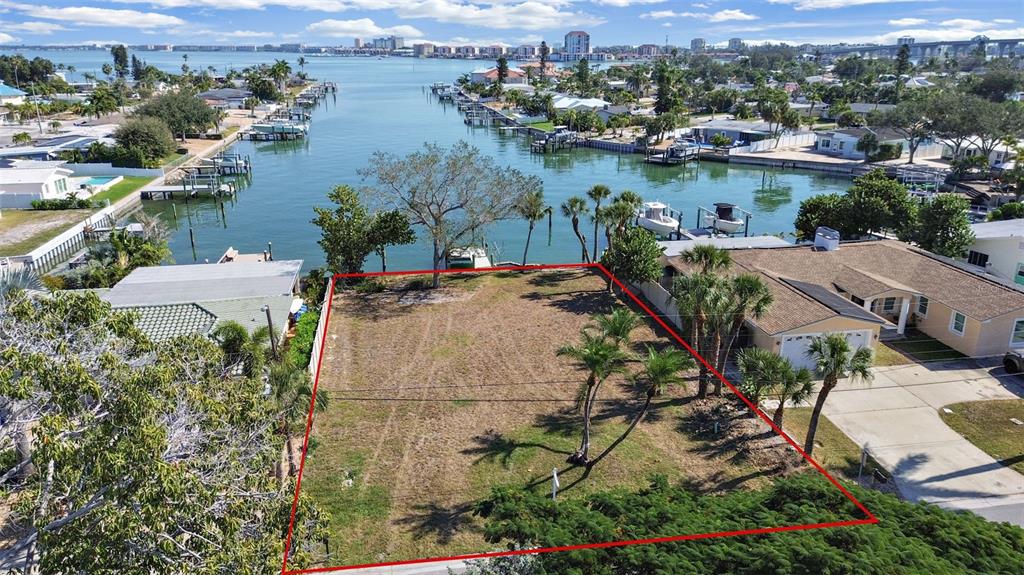 An aerial view shows a vacant waterfront lot outlined in red next to a house — 4031 POINSETTIA DRIVE, ST PETE BEACH, FL