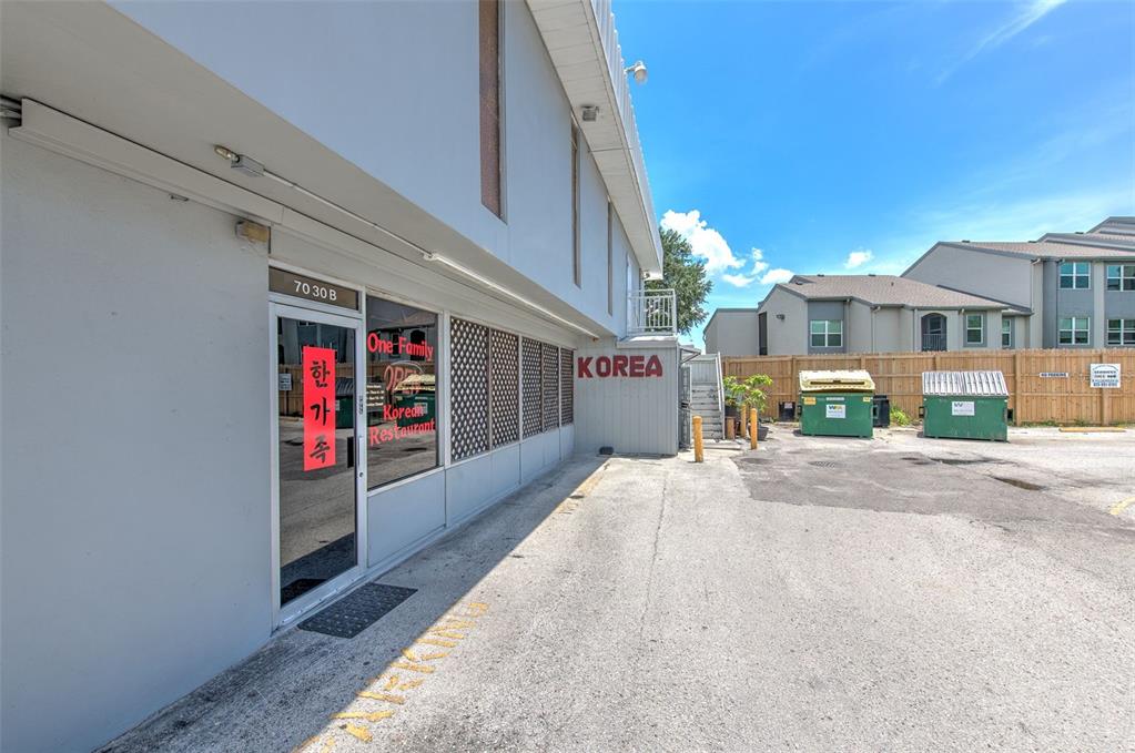 The exterior of a commercial building features a Korean restaurant entrance and two green dumpsters — 7030 W HILLSBOROUGH AVENUE UNIT Suit B, TAMPA, FL