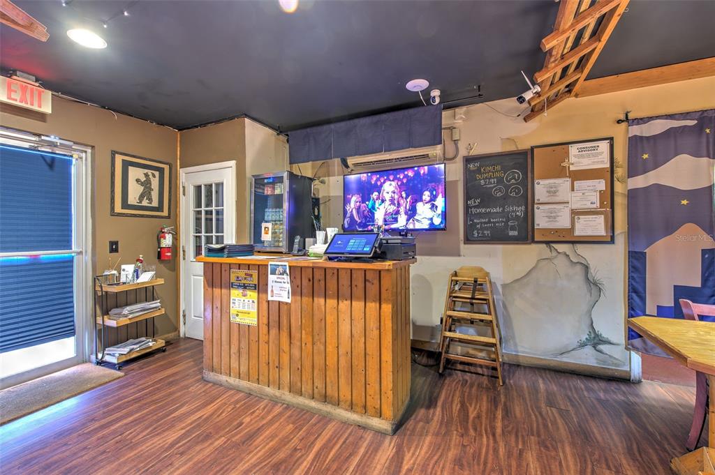 A restaurant interior features a wooden service counter, a television, and a menu chalkboard — 7030 W HILLSBOROUGH AVENUE UNIT Suit B, TAMPA, FL