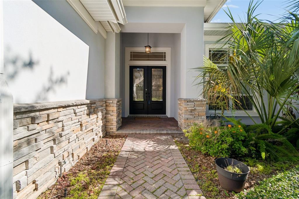 A brick walkway leads to a front entrance with double doors and stone wall accents — 2107 CARROLL LANDING DRIVE, TAMPA, FL