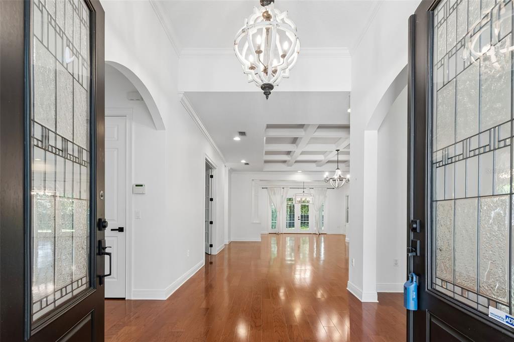 A bright foyer with hardwood floors leads into an open living area with coffered ceilings — 2107 CARROLL LANDING DRIVE, TAMPA, FL