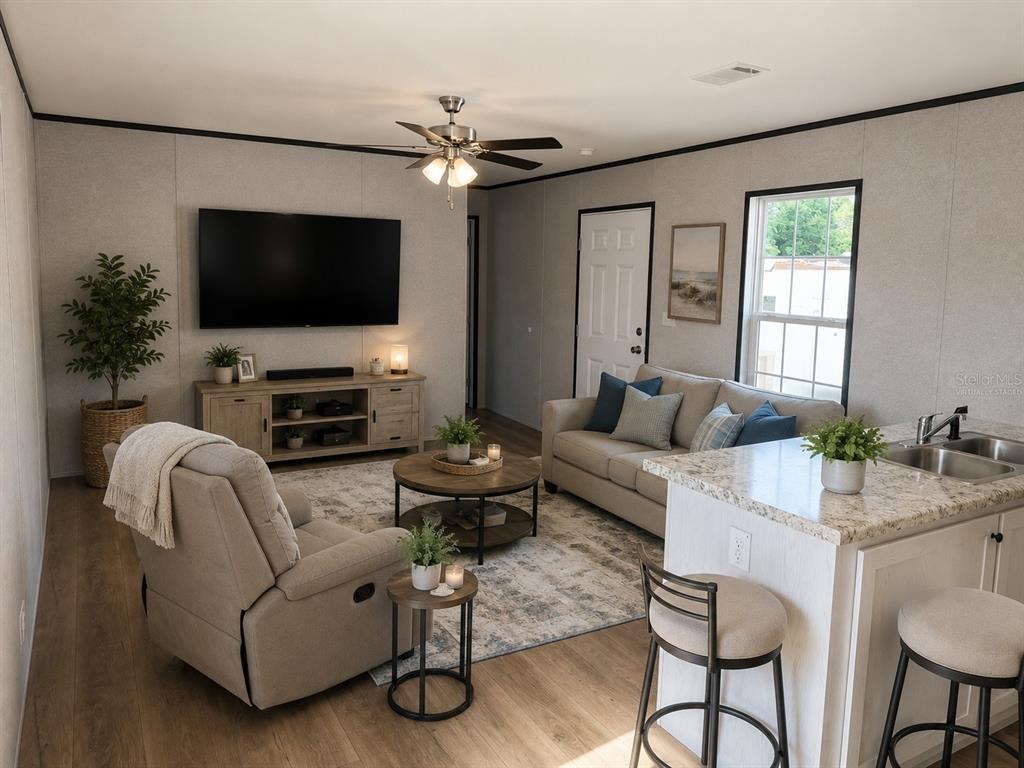 A living room features a television, sofa, recliner, and kitchen island with bar stools — 9024 KOSIMO STREET, NEW PORT RICHEY, FL
