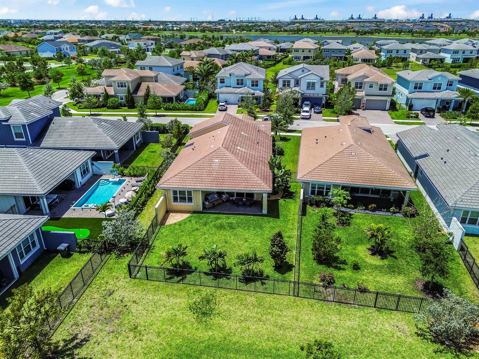 An aerial view shows suburban houses with tiled roofs, fenced backyards, and a swimming pool — 1338 Harvester Crossing, Loxahatchee FL 33470, LOXAHATCHEE, FL