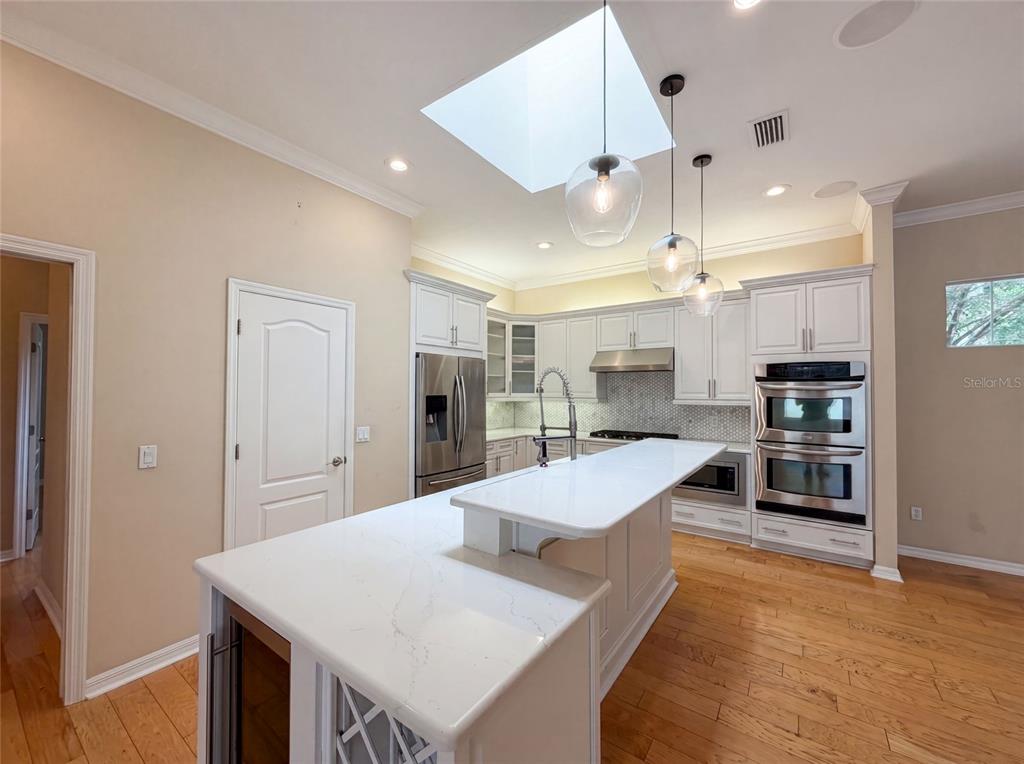 A kitchen features white cabinetry, a central island with a quartz countertop, and a skylight — 13478 NW 9TH ROAD, NEWBERRY, FL