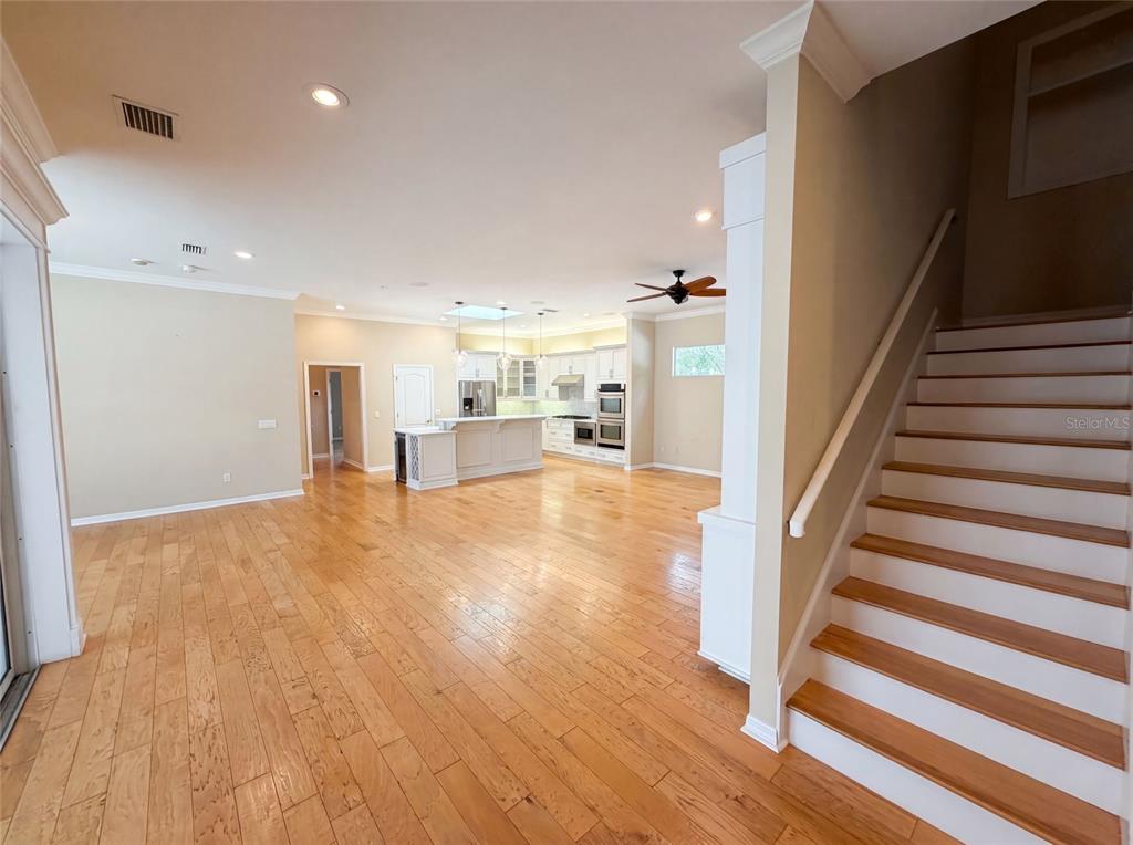 An open-concept kitchen and living area features hardwood floors and a staircase with white risers — 13478 NW 9TH ROAD, NEWBERRY, FL