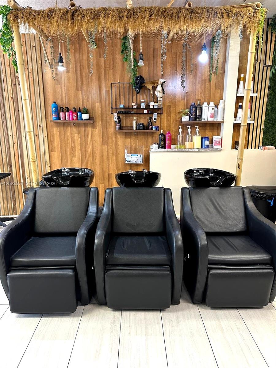 Three black shampoo chairs are positioned in front of a wood-paneled wall with shelving — 1222 Normandy DR, Miami Beach FL 33141, MIAMI BEACH, FL