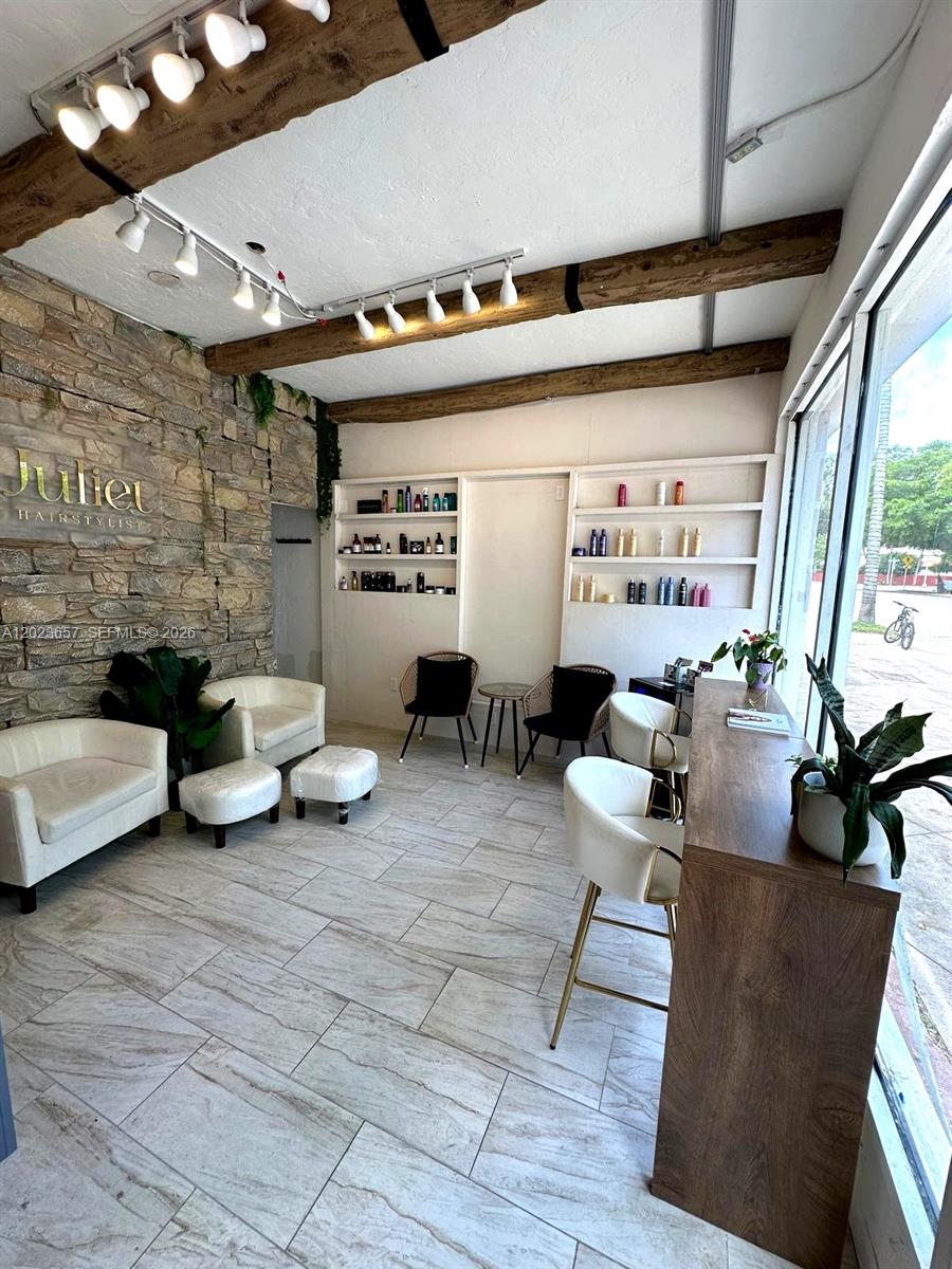 A hair salon features a stone wall, wood ceiling beams, white tile floors, and seating areas — 1222 Normandy DR, Miami Beach FL 33141, MIAMI BEACH, FL