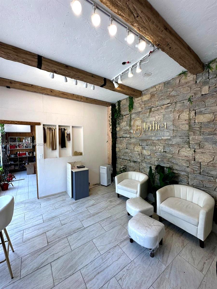 A waiting area features a stone wall, wood ceiling beams, and two white armchairs — 1222 Normandy DR, Miami Beach FL 33141, MIAMI BEACH, FL