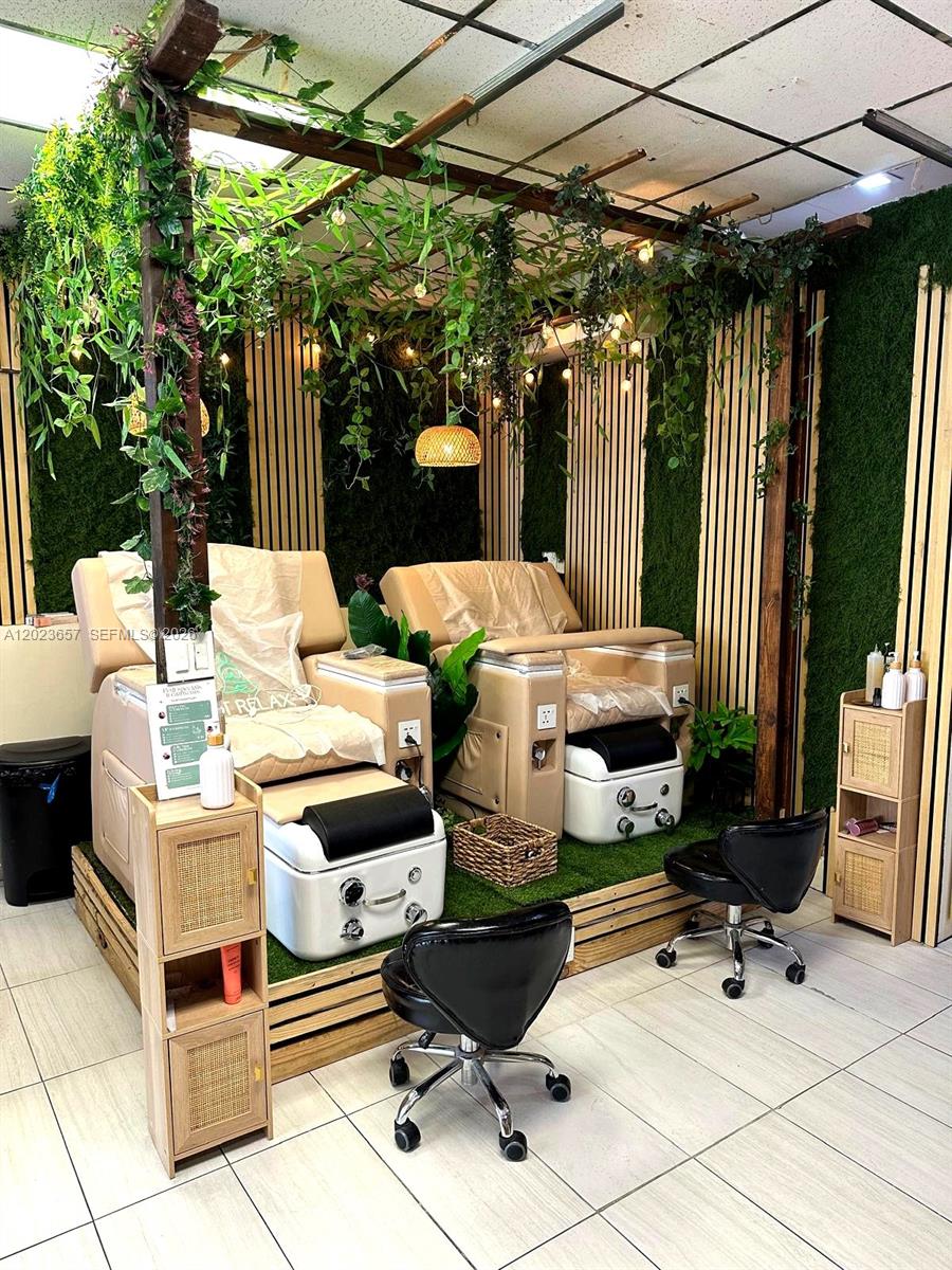 Two pedicure chairs sit on a raised wooden platform decorated with artificial greenery and lights — 1222 Normandy DR, Miami Beach FL 33141, MIAMI BEACH, FL