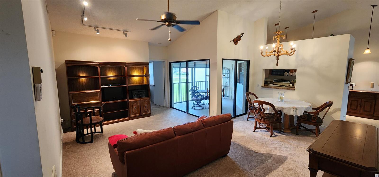 A living and dining area with a leather sofa, built-in shelving, and a glass-topped table — 6043 Parkwalk Drive, Boynton Beach FL 33472, BOYNTON BEACH, FL