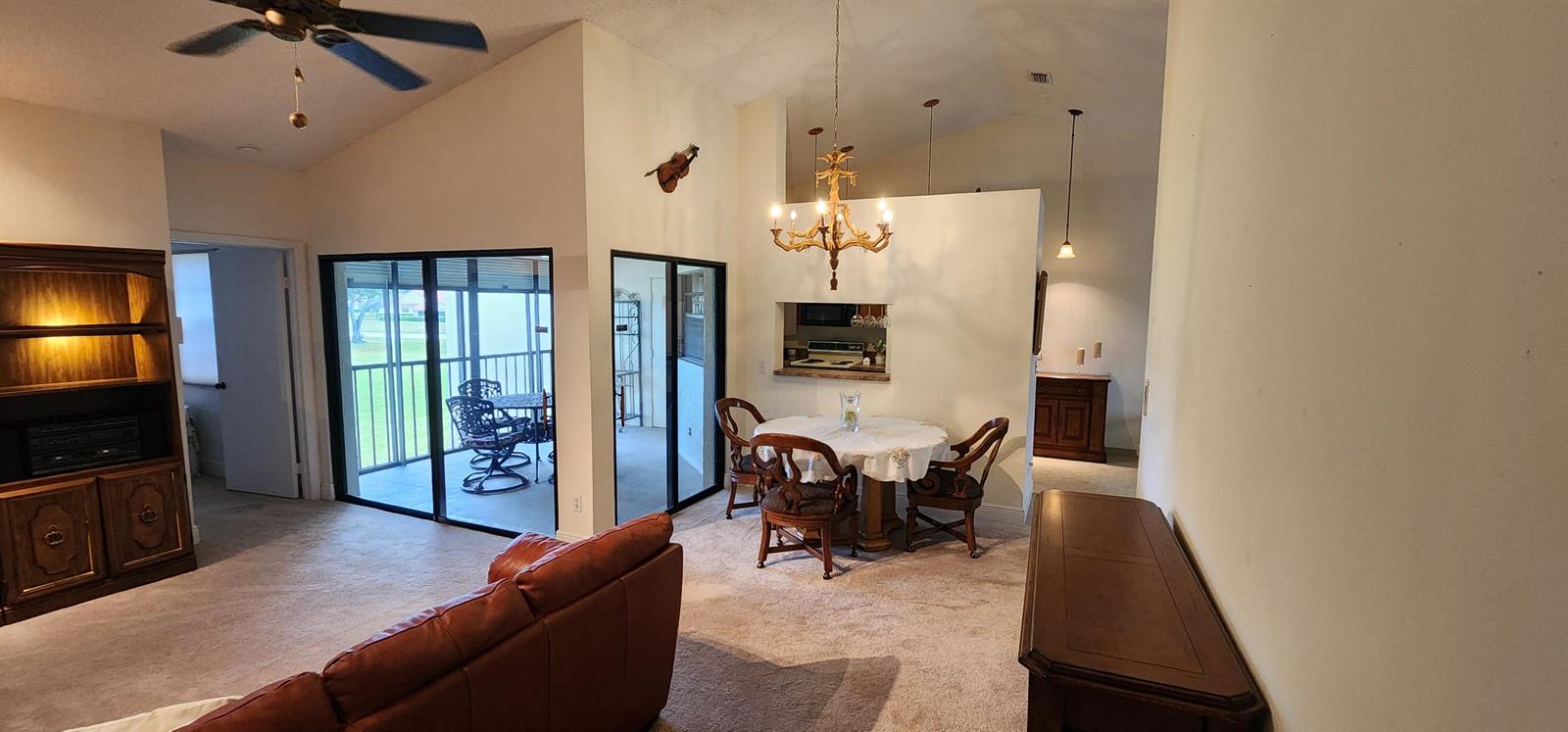 A living and dining area with carpeted floors, a chandelier, and a sliding glass door — 6043 Parkwalk Drive, Boynton Beach FL 33472, BOYNTON BEACH, FL