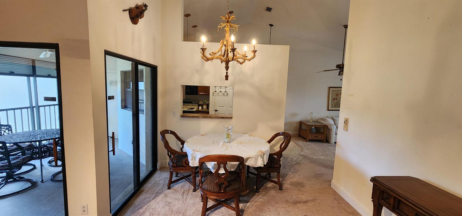 A dining area with a chandelier, round table, and a pass-through window to the kitchen — 6043 Parkwalk Drive, Boynton Beach FL 33472, BOYNTON BEACH, FL