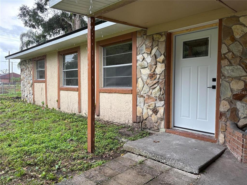 A single-story house exterior features a white front door, stone accents, and a covered porch — 2035 VOLTAIRE STREET, LAKELAND, FL