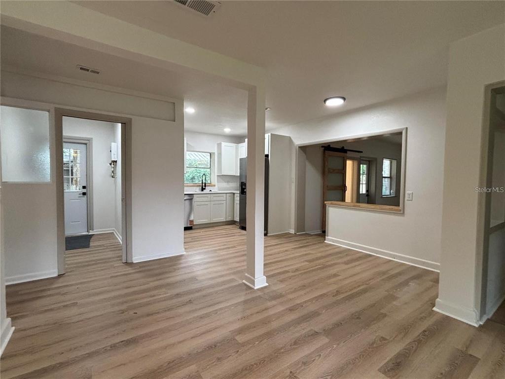 An open-concept interior features light wood-look flooring, white walls, and a kitchen with white cabinets — 2035 VOLTAIRE STREET, LAKELAND, FL