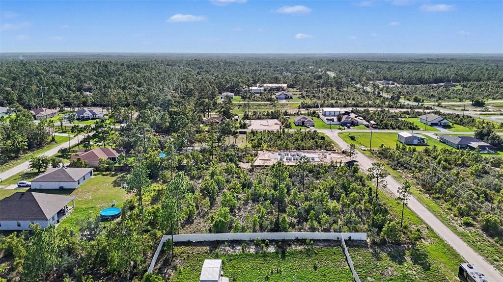 An aerial view shows a residential neighborhood with houses, wooded lots, and a construction site — 0 SCISSORBILL AVENUE, WEEKI WACHEE, FL