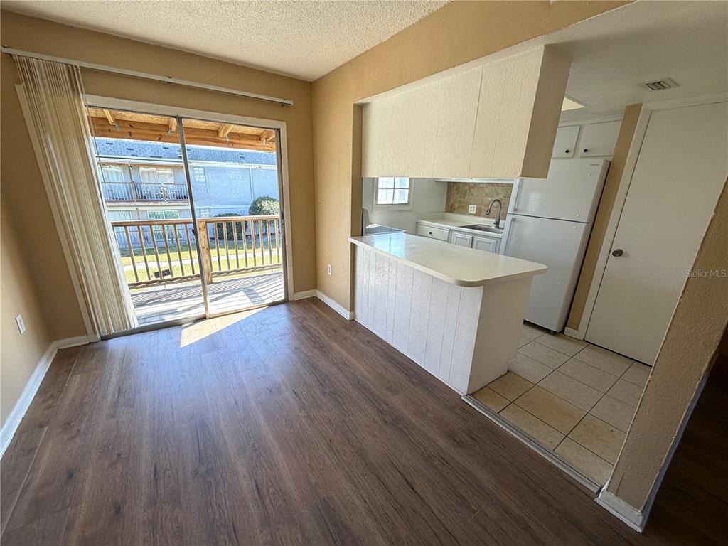 A dining area with wood-look flooring leads to a kitchen with a breakfast bar — 2785 L B MCLEOD ROAD UNIT 2785D, ORLANDO, FL