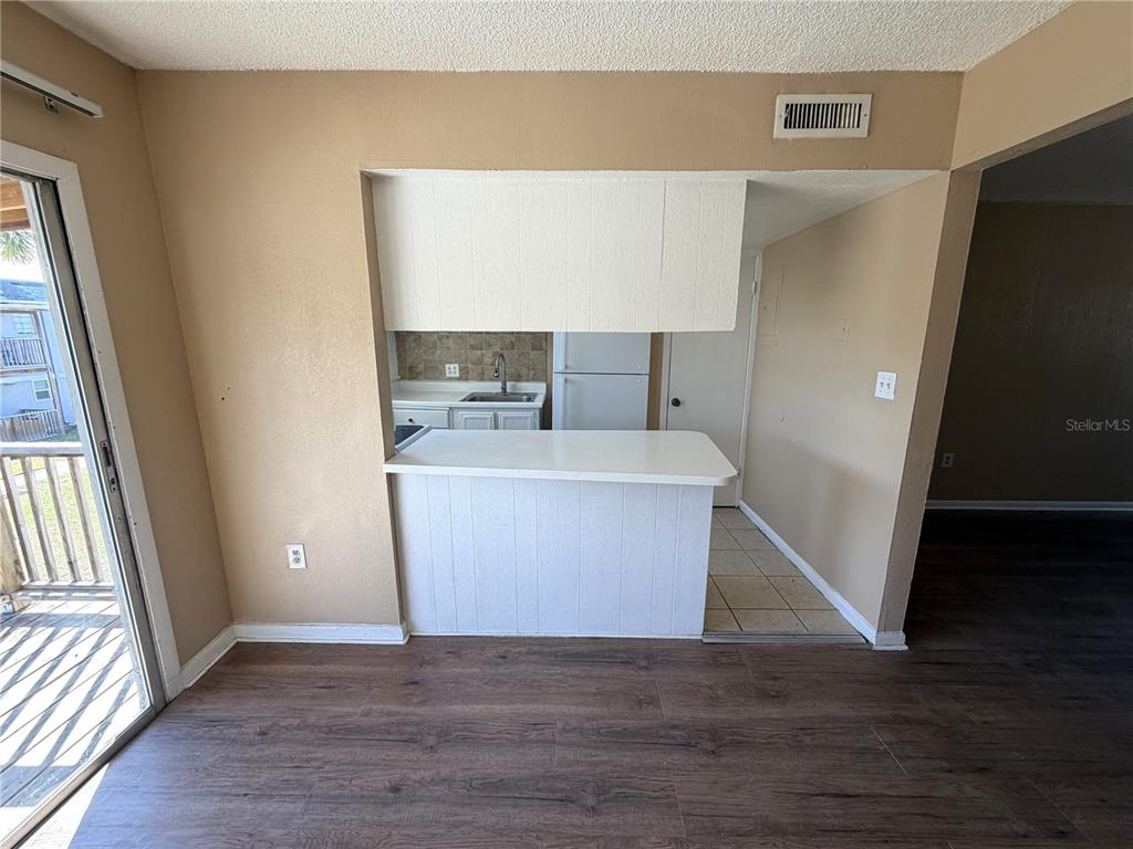 A kitchen with a breakfast bar, white cabinets, and wood-look flooring viewed from an adjacent room — 2785 L B MCLEOD ROAD UNIT 2785D, ORLANDO, FL