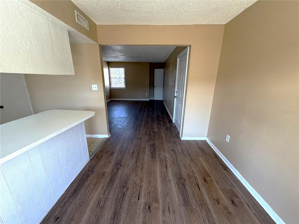 An interior view shows a kitchen counter overlooking a living area with wood-look flooring — 2785 L B MCLEOD ROAD UNIT 2785D, ORLANDO, FL