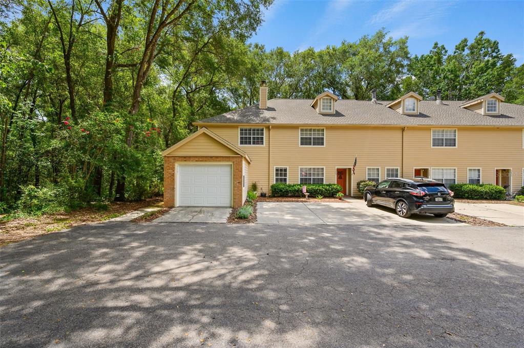 A two-story tan townhouse with a single-car garage and a paved driveway — 5261 SW 97TH DRIVE, GAINESVILLE, FL