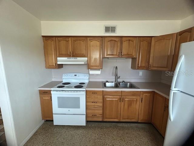 A kitchen features wood cabinets, a white stove, a double sink, and speckled flooring — 2518 40TH AVENUE N, ST PETERSBURG, FL