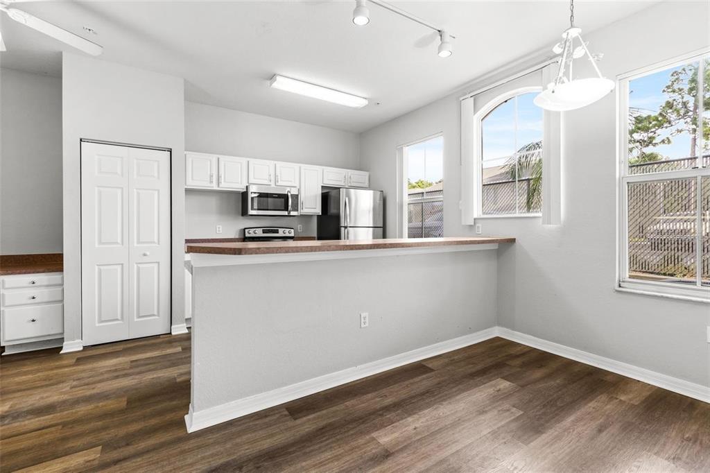 A kitchen with white cabinets, stainless steel appliances, and a breakfast bar overlooks a dining area — 5009 SUNRIDGE PALMS DRIVE UNIT 203, TAMPA, FL