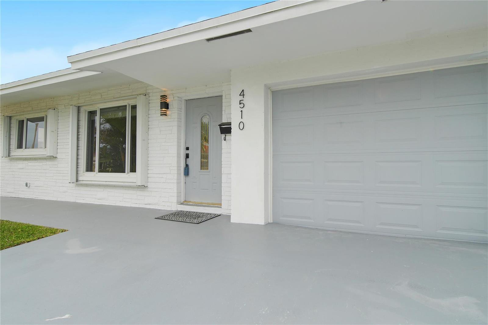 A white brick house exterior features a gray front door, garage door, and concrete driveway — 4510 NW 49th Drive, Tamarac FL 33319, TAMARAC, FL