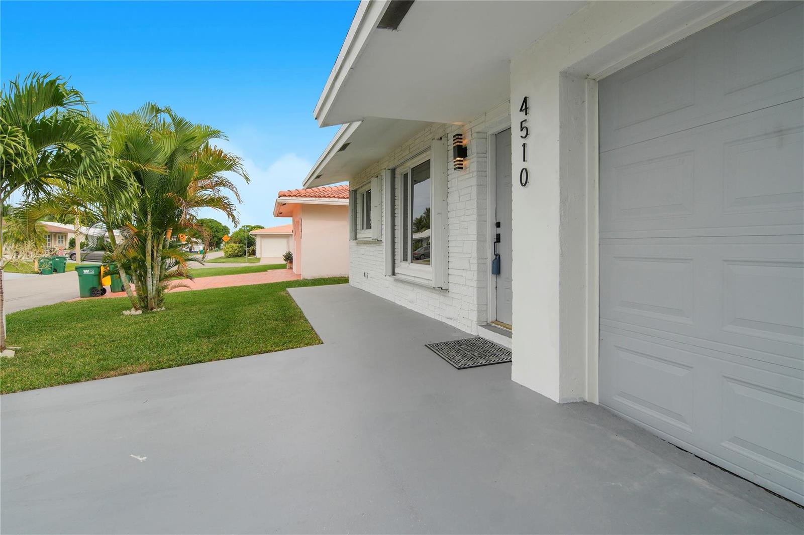 A white brick house exterior features a gray garage door and a concrete driveway — 4510 NW 49th Drive, Tamarac FL 33319, TAMARAC, FL