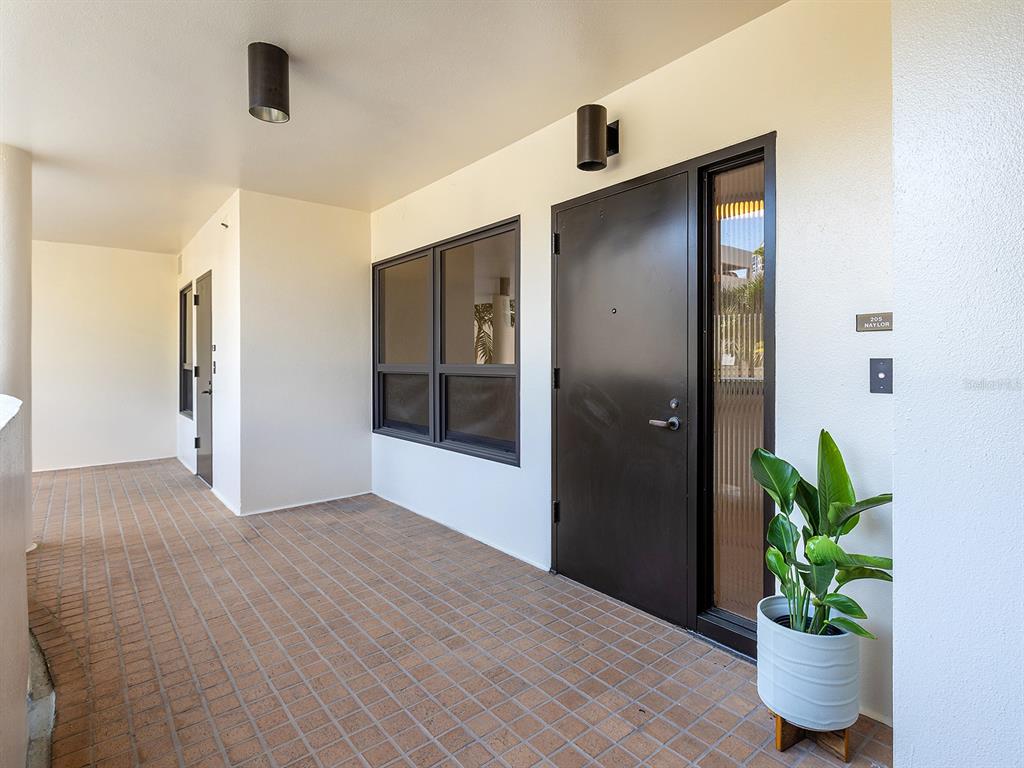 An exterior walkway features a tiled floor, dark doors, and a potted plant — 1255 N GULFSTREAM AVENUE UNIT 205, SARASOTA, FL
