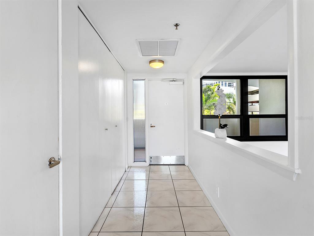 A tiled entryway features a white door, a side window, and a large closet — 1255 N GULFSTREAM AVENUE UNIT 205, SARASOTA, FL