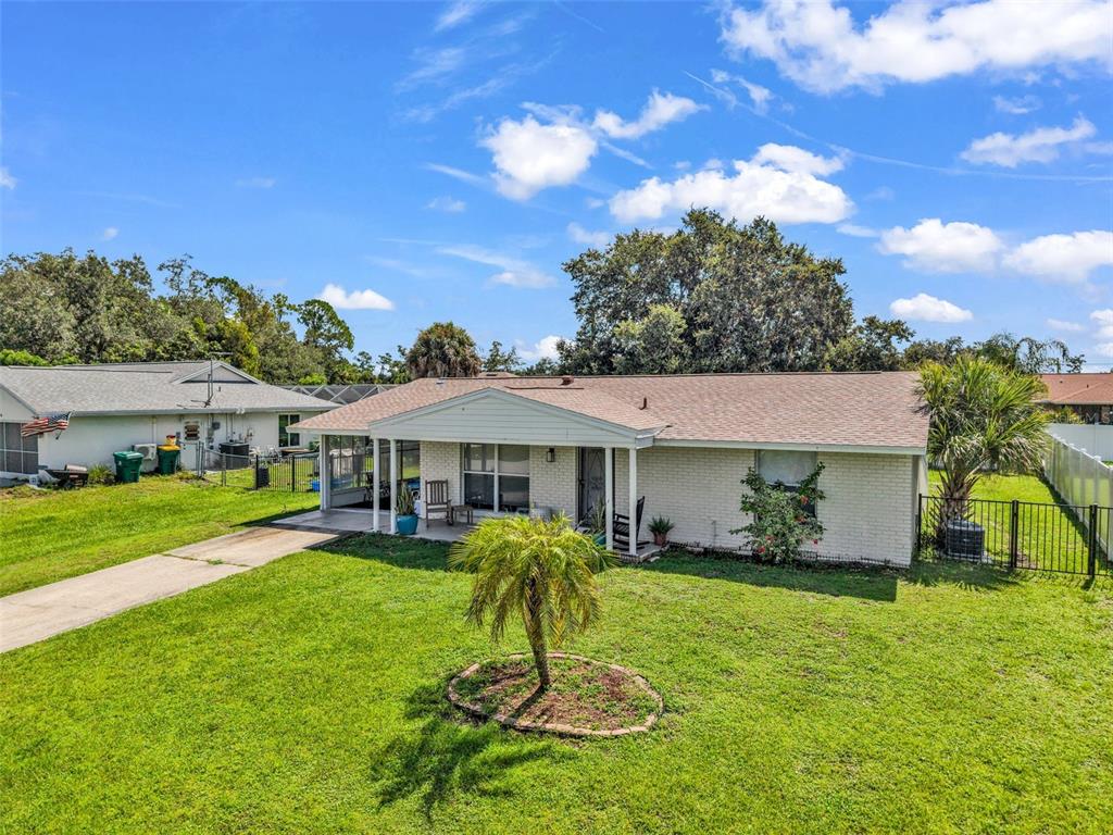 A single-story brick house with a covered porch, a small palm tree, and a lawn — 394 KOSTNER STREET, PORT CHARLOTTE, FL