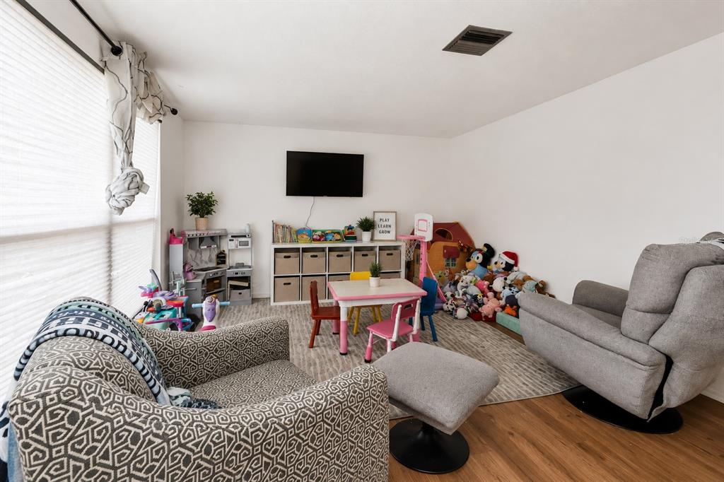 A playroom features a television, storage cubbies, a small table with chairs, and two armchairs — 394 KOSTNER STREET, PORT CHARLOTTE, FL