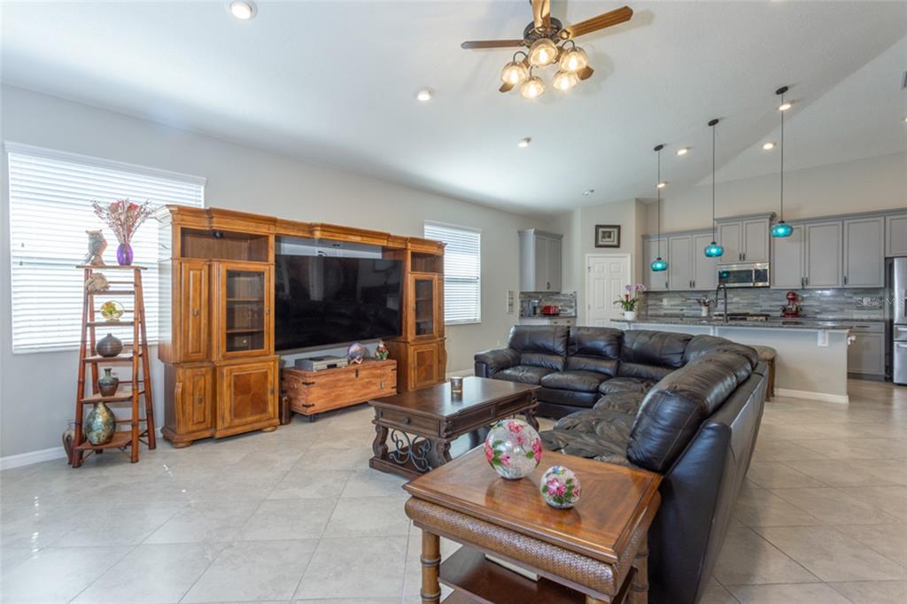 A living room with tile floors, a large entertainment center, and an open kitchen — 43 LAGOON WAY, PALM COAST, FL