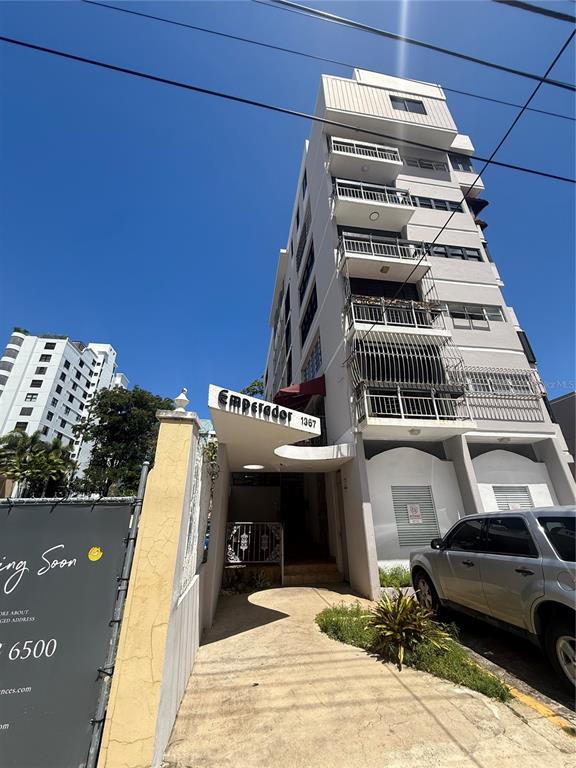 A multi-story apartment building with balconies and a covered entrance stands next to a street — 1367 WILSON UNIT 401, SAN JUAN, PR