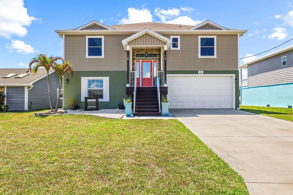 A two-story house with tan and green siding, a red front door, and a driveway — 3351 POINSETTIA DRIVE, HERNANDO BEACH, FL