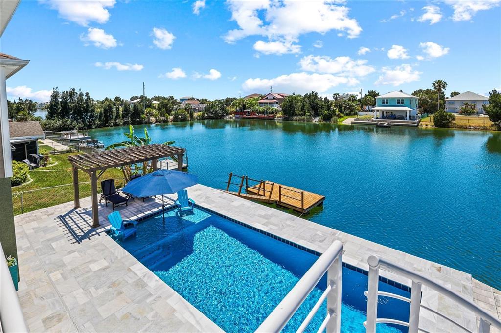 An elevated view of a swimming pool, pergola, and wooden dock overlooking a calm lake — 3351 POINSETTIA DRIVE, HERNANDO BEACH, FL
