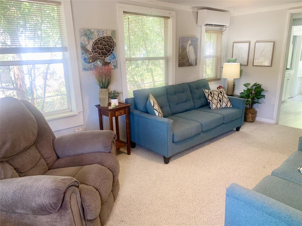 A living room features a blue sofa, a brown recliner, and two windows with blinds — 4836 19TH STREET, ZEPHYRHILLS, FL