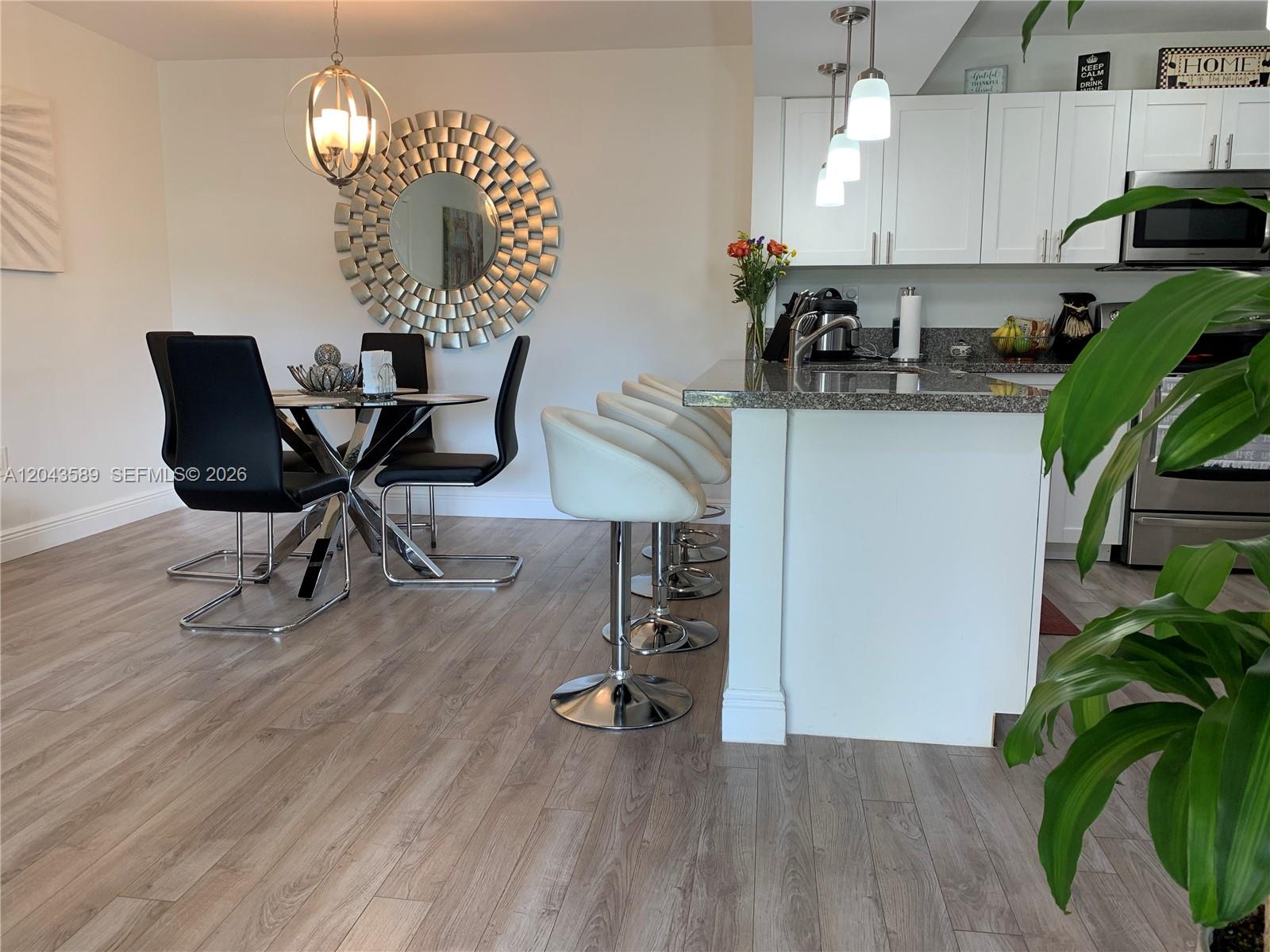 A dining area with a round table and a kitchen island with white bar stools — 8660 SW 212th St # 305, Cutler Bay FL 33189, CUTLER BAY, FL