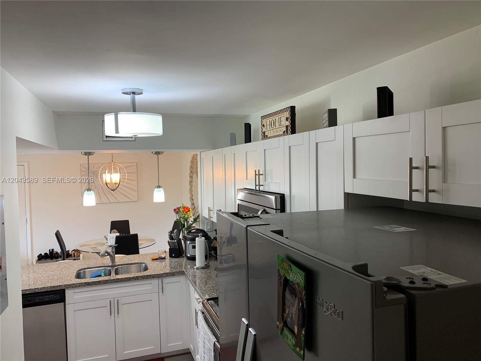 A kitchen features white cabinets, granite countertops, stainless steel appliances, and an adjacent dining area — 8660 SW 212th St # 305, Cutler Bay FL 33189, CUTLER BAY, FL